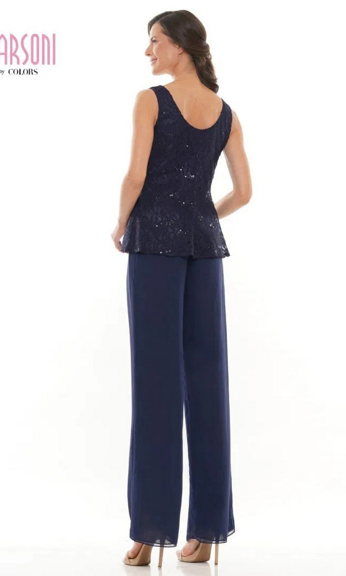 A woman stands facing away in the Marsoni M305 long formal pantsuit—sleeveless navy blue sequin top with matching chiffon pants and beige heels—set against a plain white background.